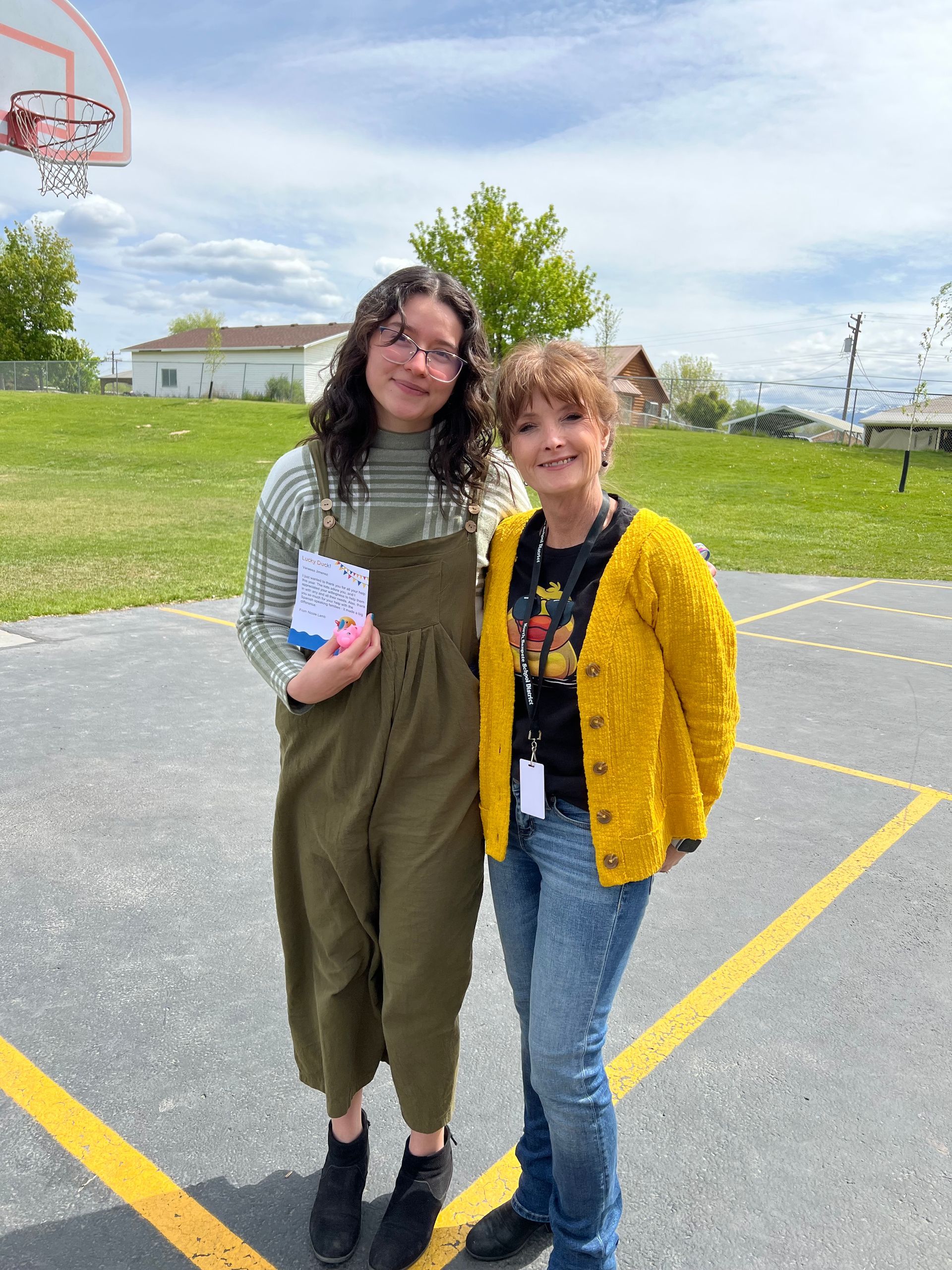 Two women are standing next to each other in a parking lot.