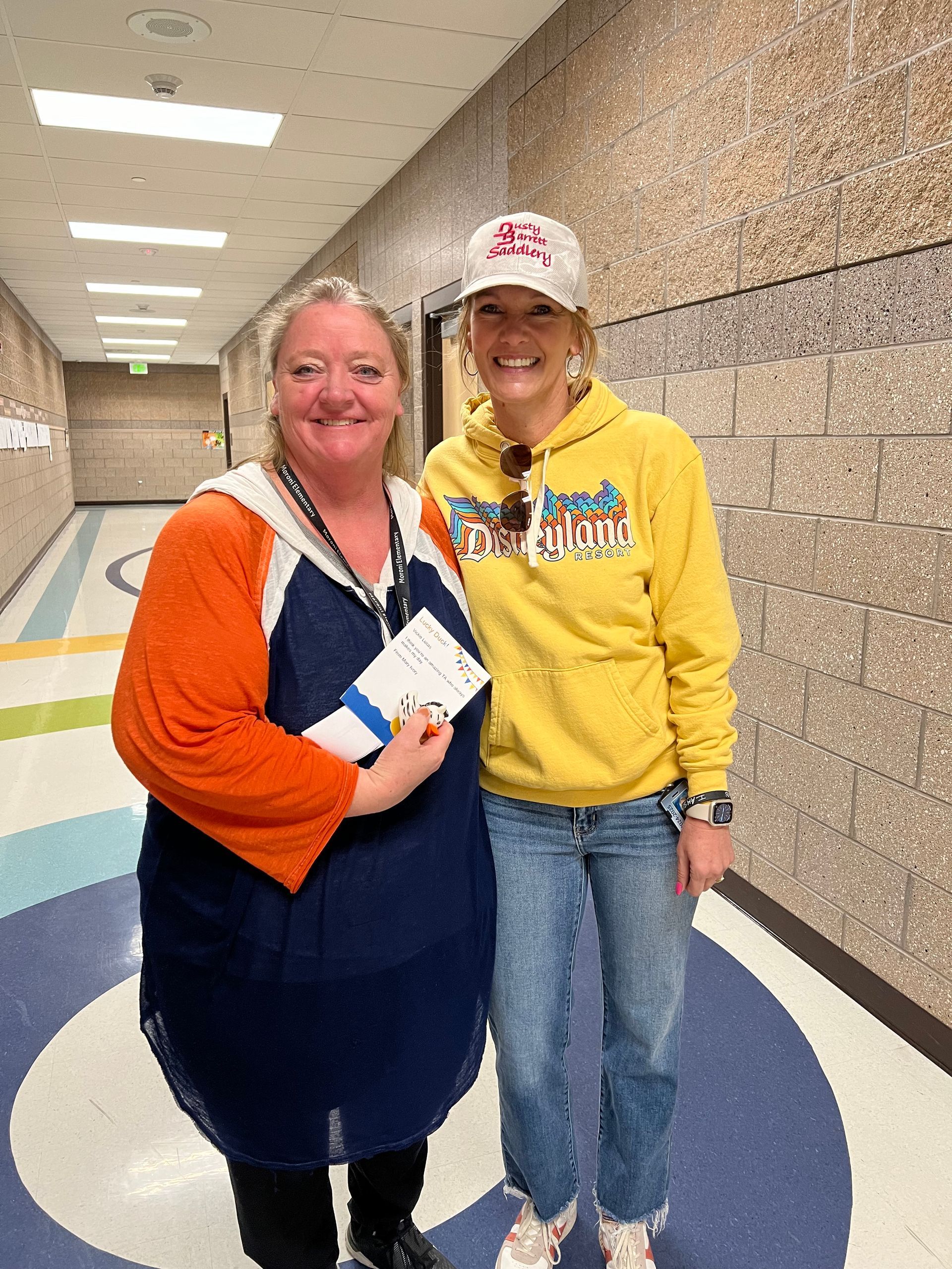 Two women are standing next to each other in a hallway.