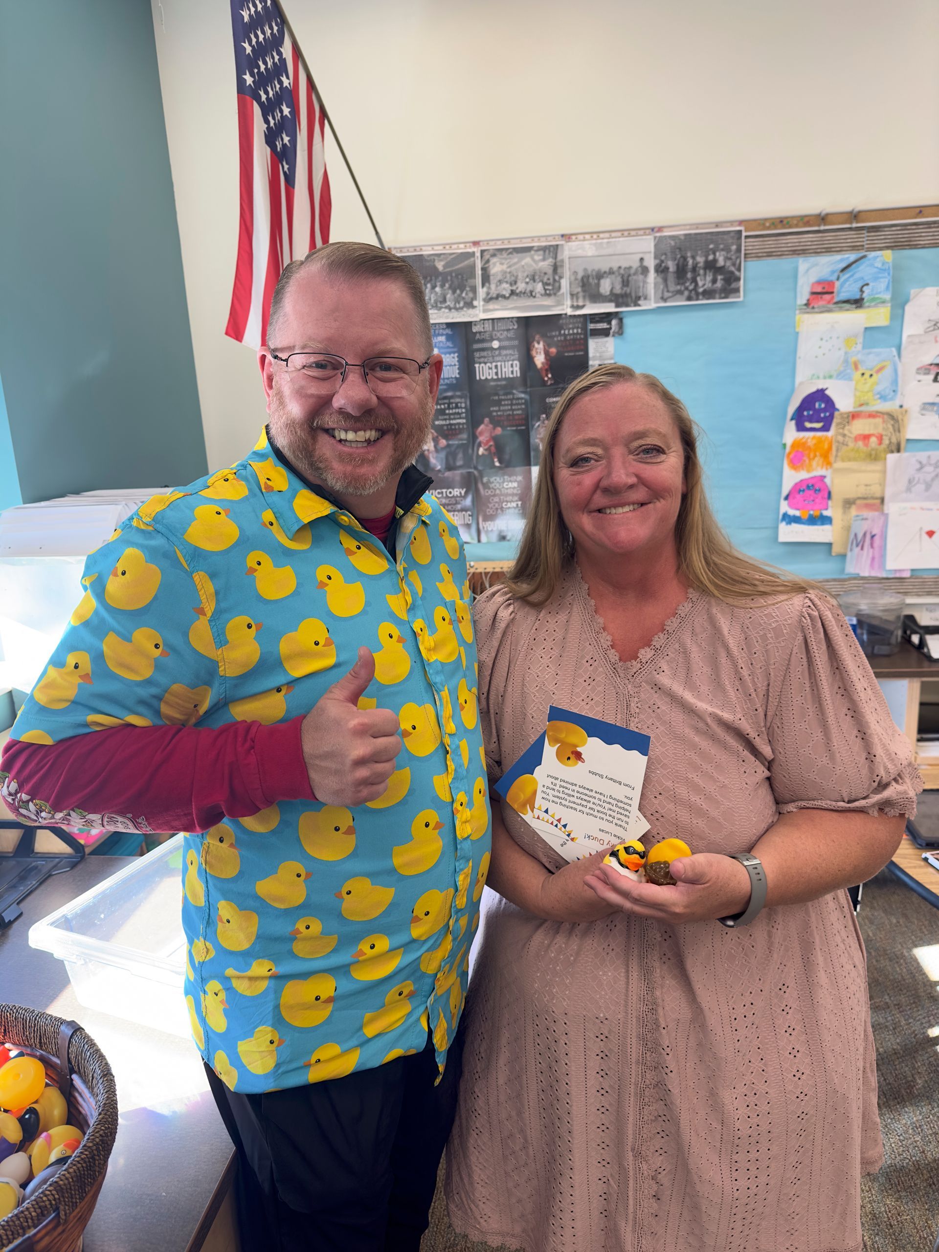 A man in a rubber duck shirt is standing next to a woman in a pink dress.