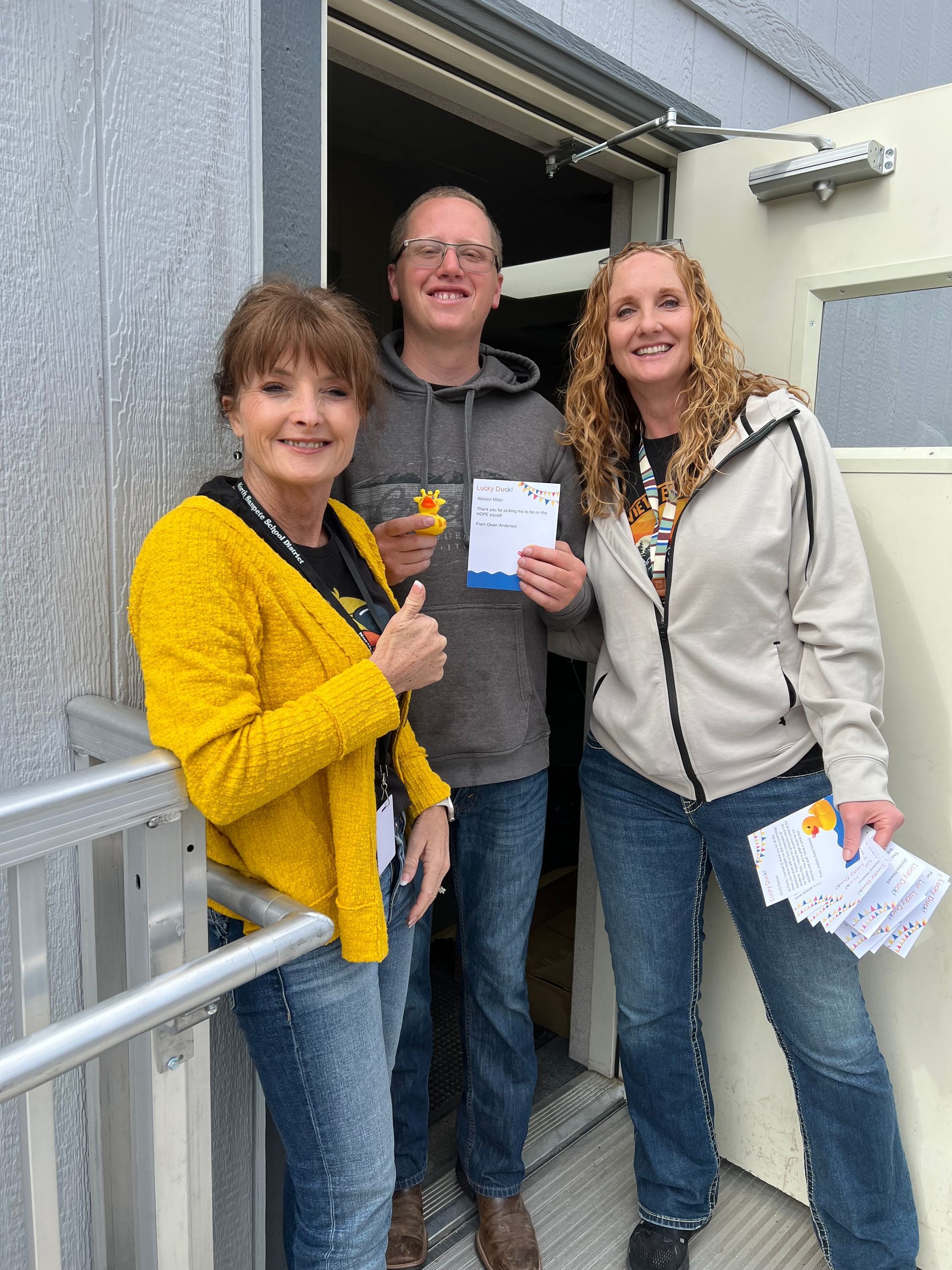 A man and two women are standing in front of a door.