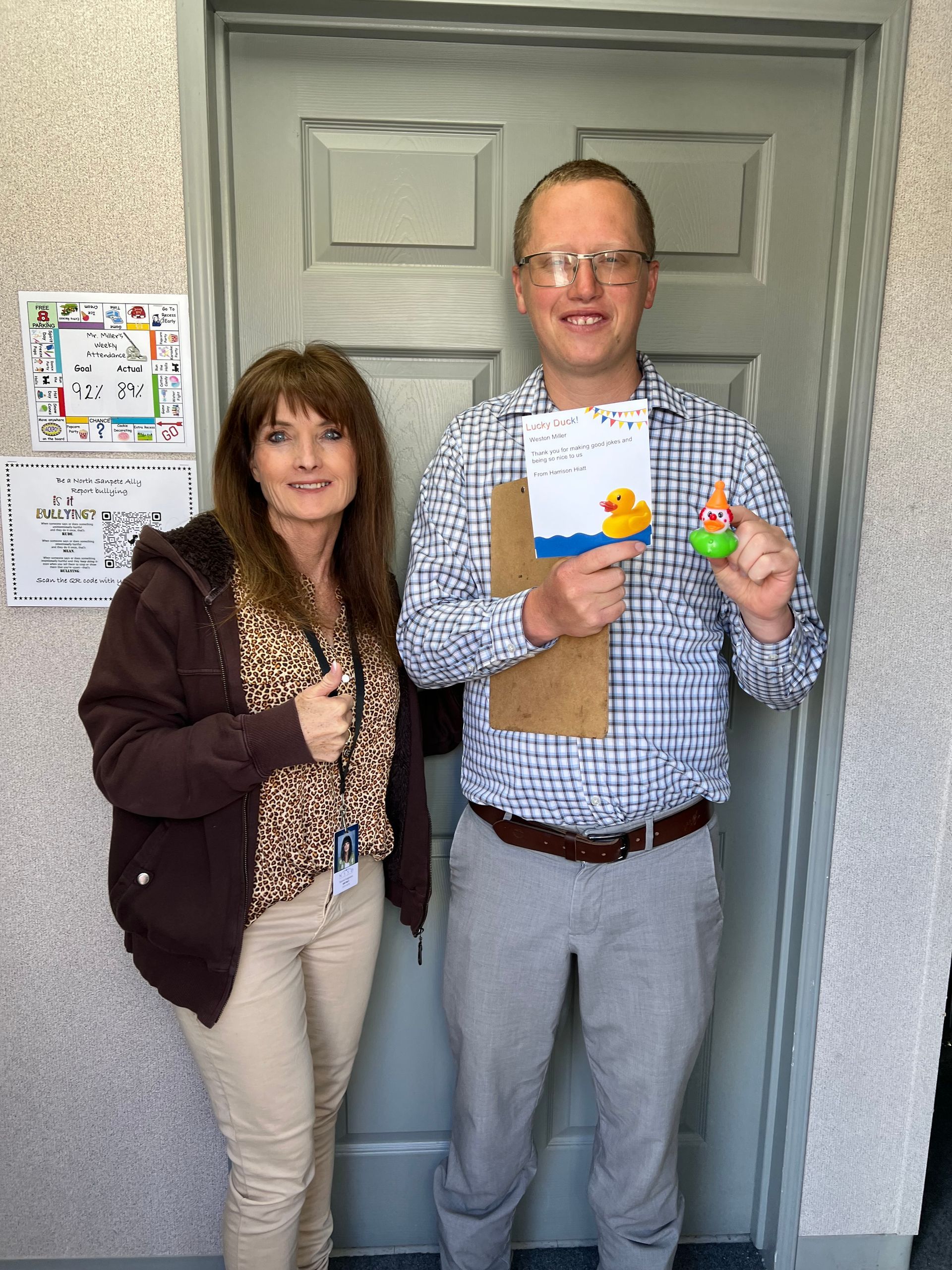 A man and a woman are standing next to each other in front of a door holding rubber ducks.