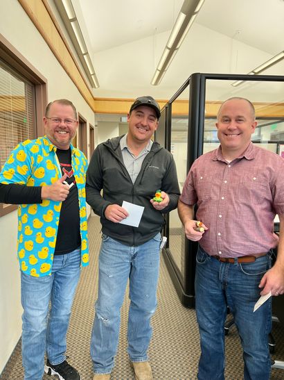 Three men are standing next to each other in a hallway.