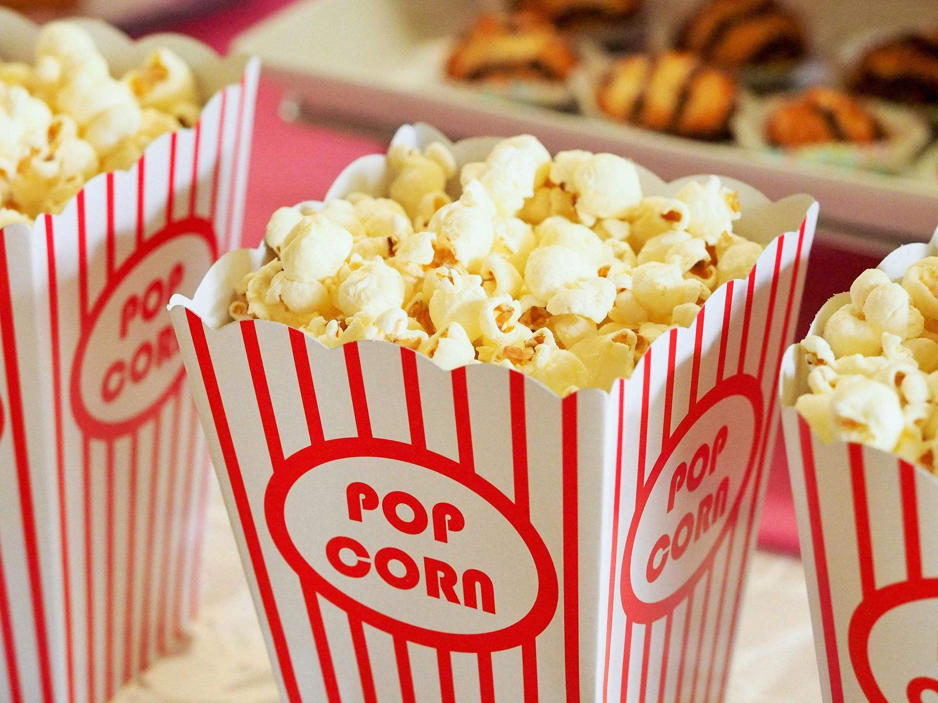 Three striped containers of popcorn are sitting on a table.