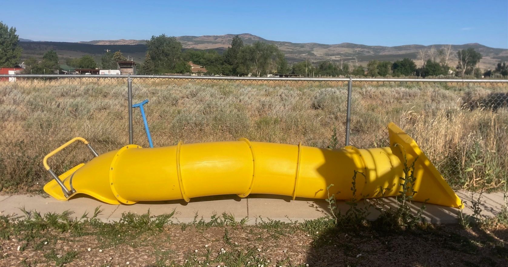 A yellow pipe is laying on the ground in a field.