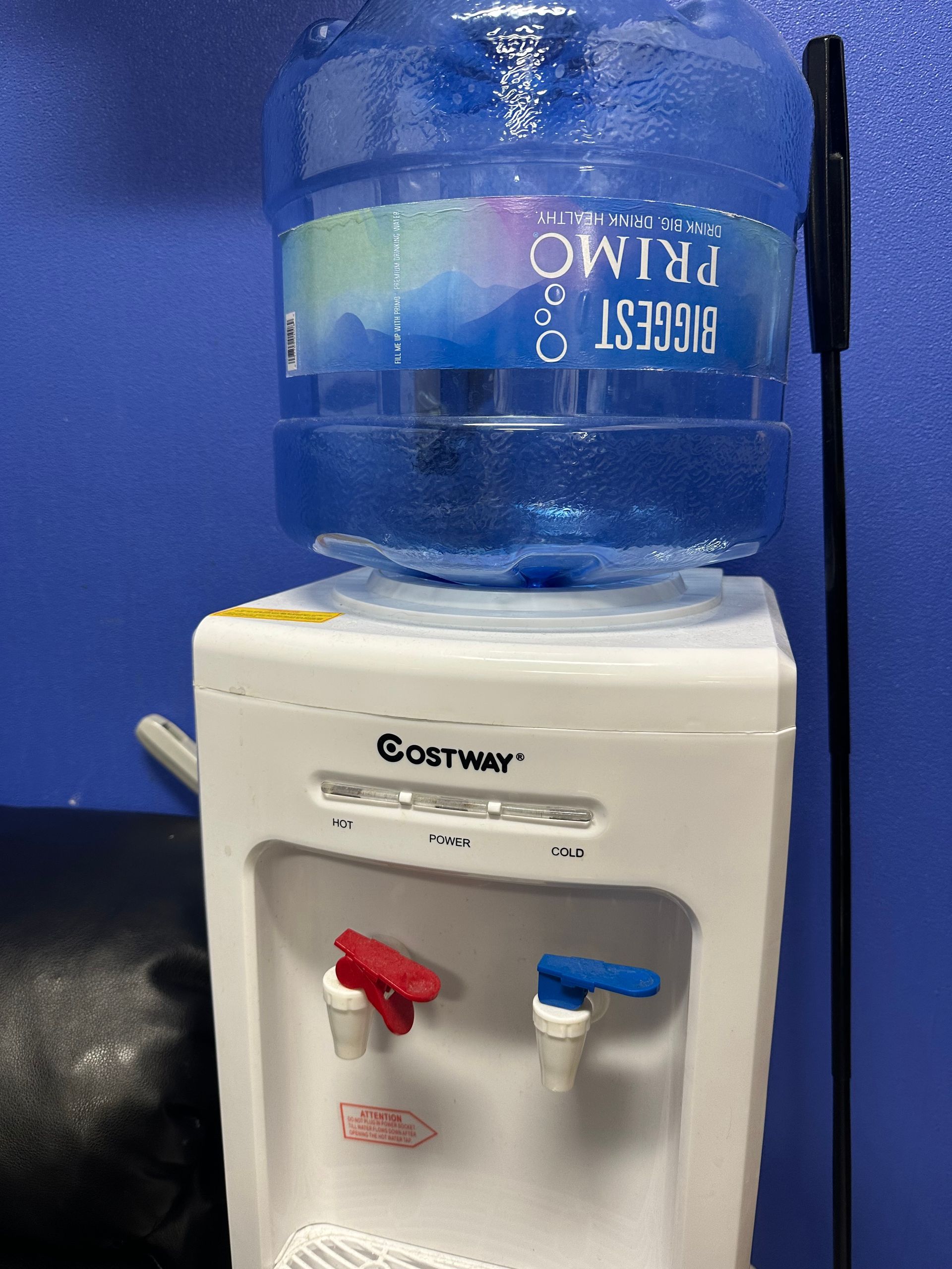 A bottle of primo water sits on top of a costino water dispenser