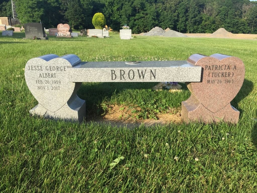 A gray stone bench with heart-shaped ends and the name 