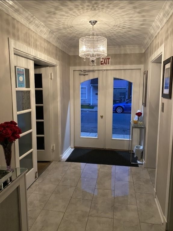 Hallway with double doors, chandelier, and a car visible through the doors.