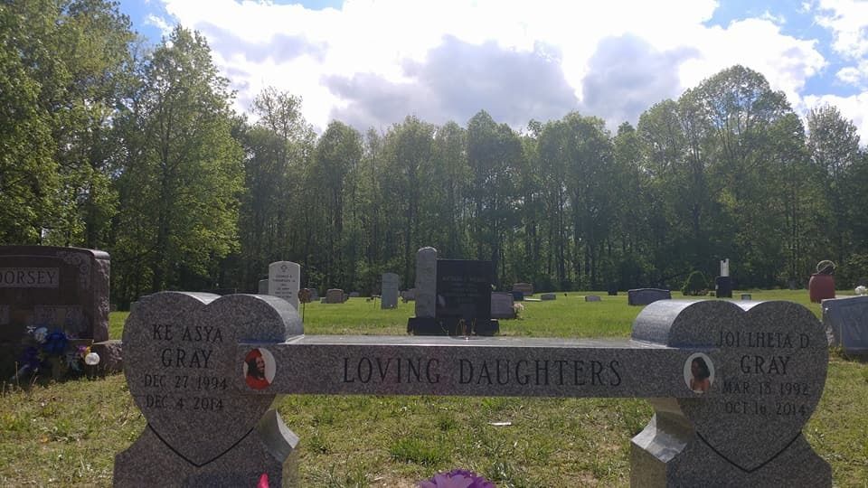 Headstones in a cemetery; a memorial bench reads 