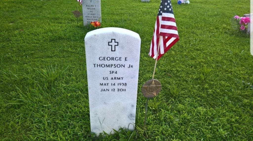 Tombstone for George E. Thompson Jr., a U.S. Army veteran. White headstone with a cross and American flag.
