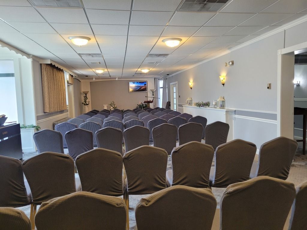 Rows of chairs face a stage in a room with a light gray color scheme.