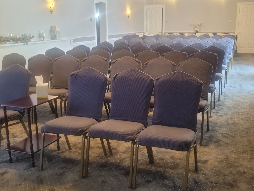 Rows of blue upholstered chairs in an empty room, possibly for a ceremony. Gold chair legs.