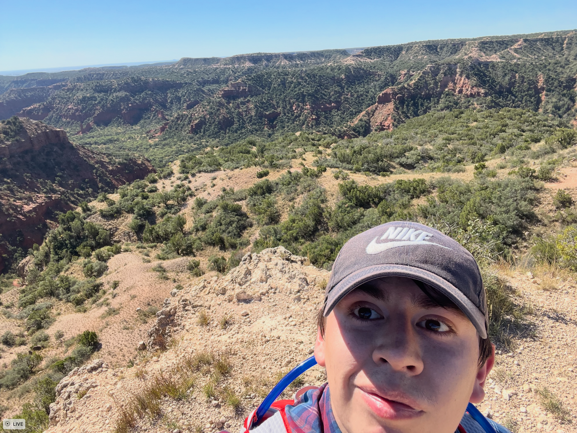 A young man wearing a nike hat is standing on top of a mountain.