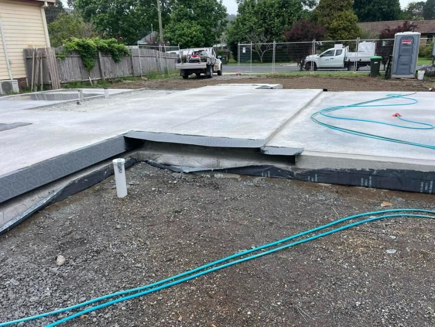 A Hose is Laying on the Ground Next to a Concrete Slab — TC Pest & Termite Control In Bowral, NSW
