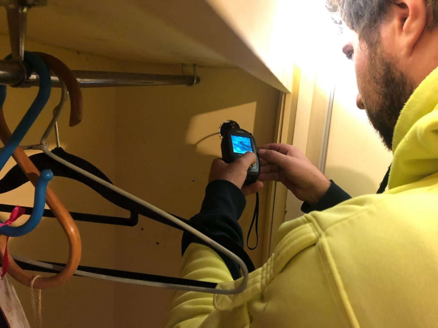 A Man is Inspecting for Termites on a Closet — TC Pest & Termite Control In Bowral, NSW