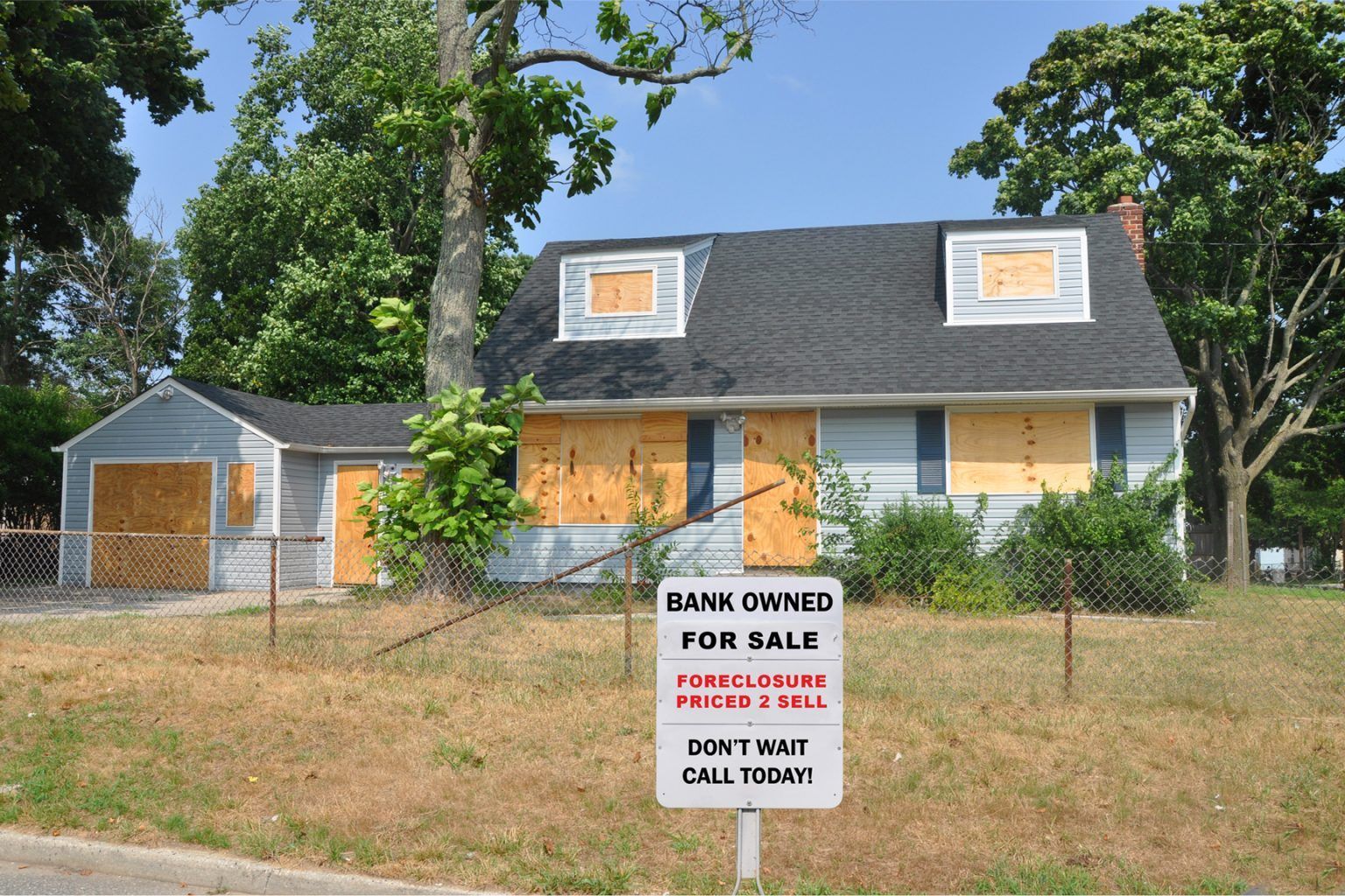 A house with a bank owned for sale sign in front of it