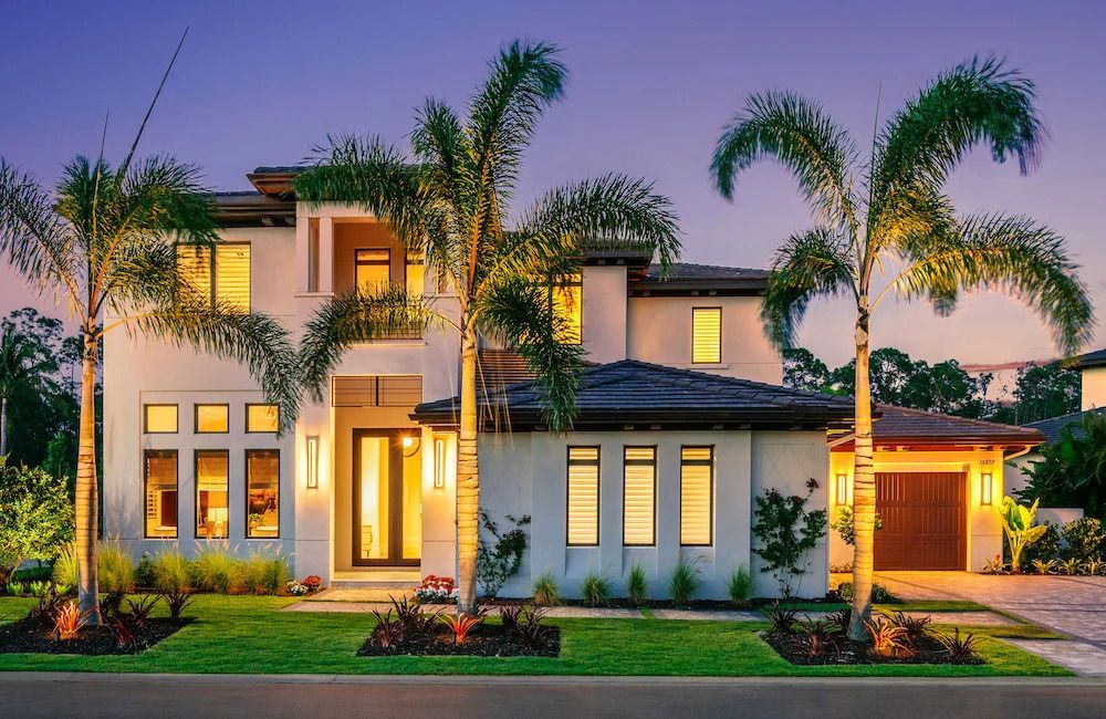 A large white house with palm trees in front of it.