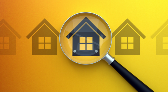 A magnifying glass is looking at a house on a yellow background.