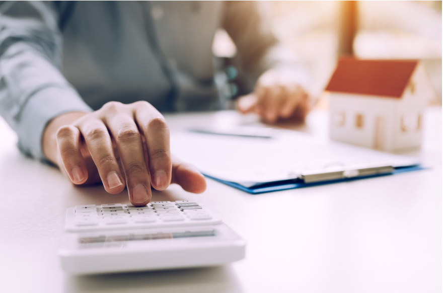 A man is using a calculator to calculate the cost of a house.