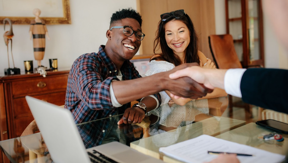 A man and a woman are shaking hands with a real estate agent.