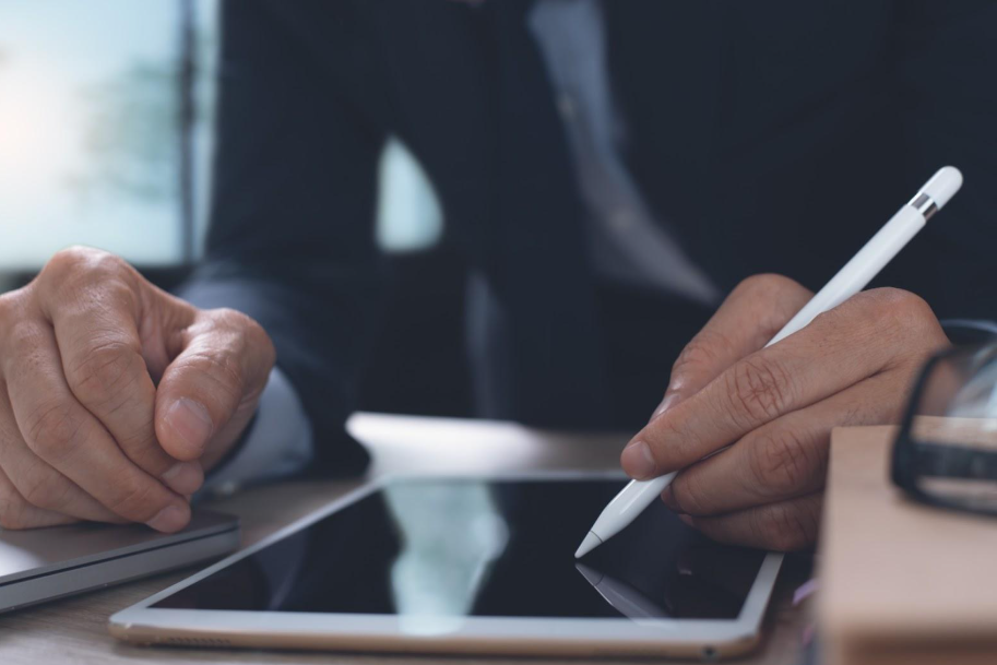 A person is writing on a tablet with a pencil.