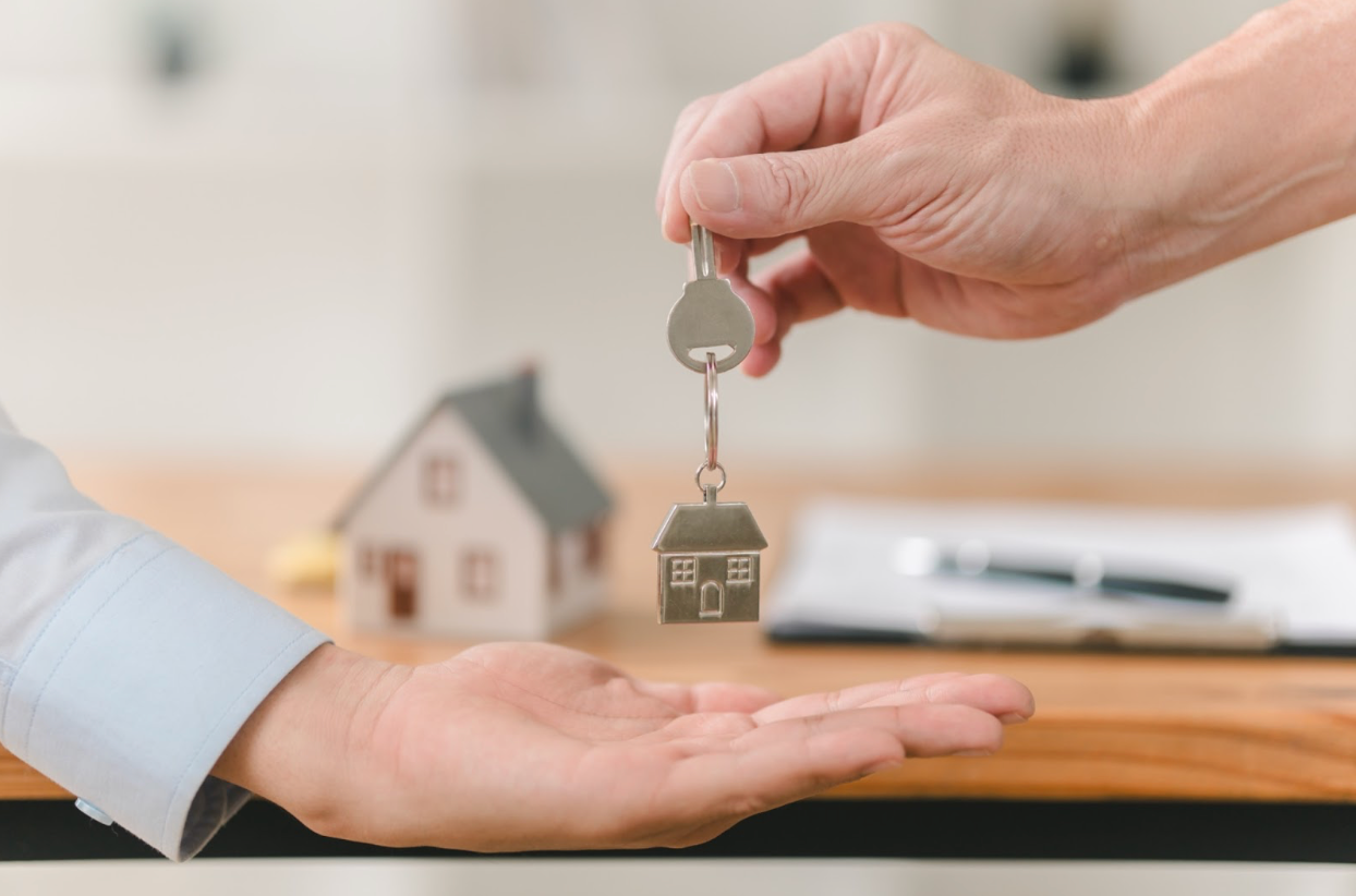 A person is handing a house key to another person.