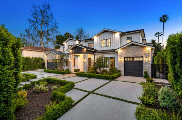 Modern two-story luxury home at dusk with white and stone exterior, black trim, large driveway with