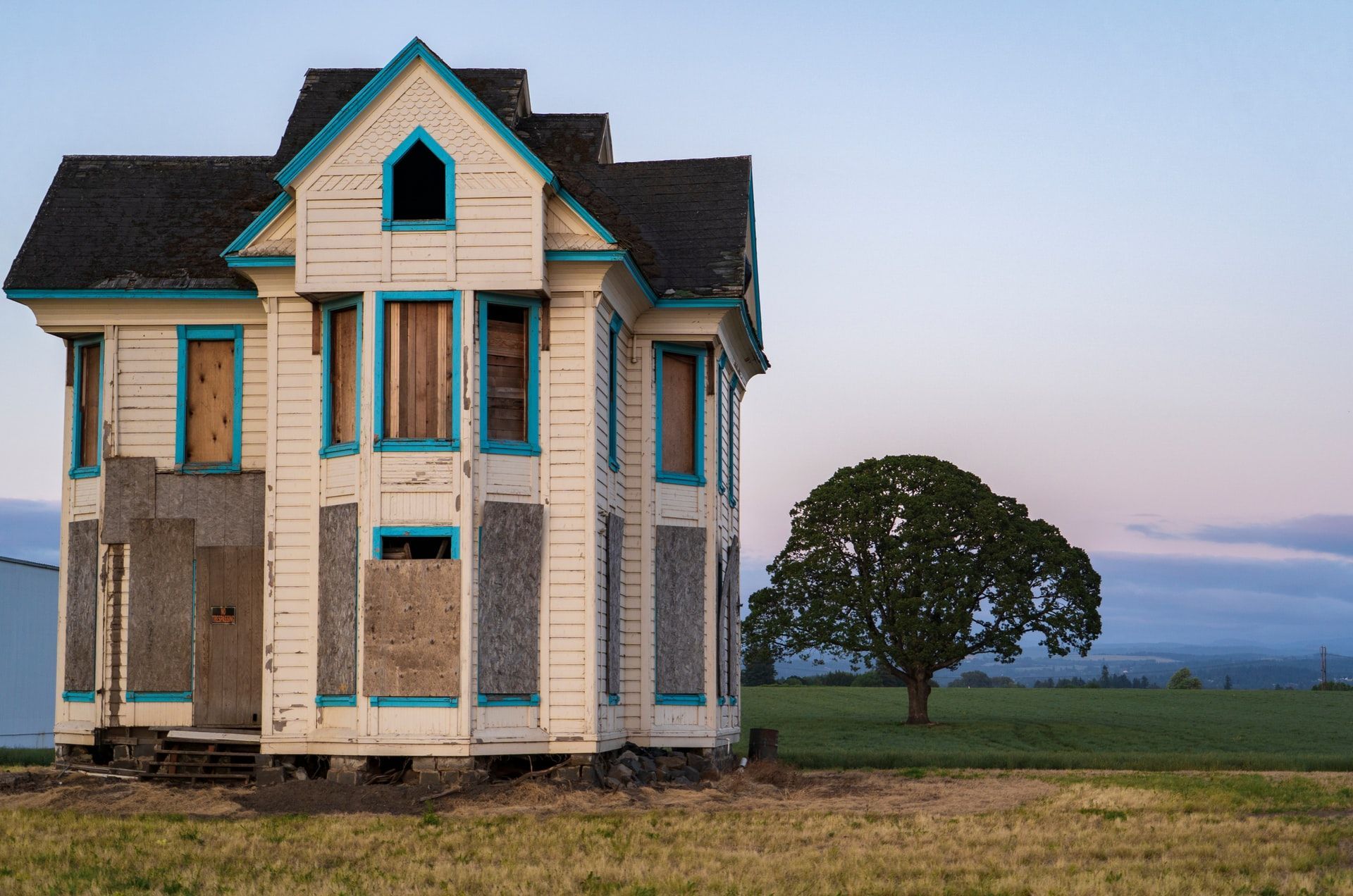 An old abandoned house with a tree in the background