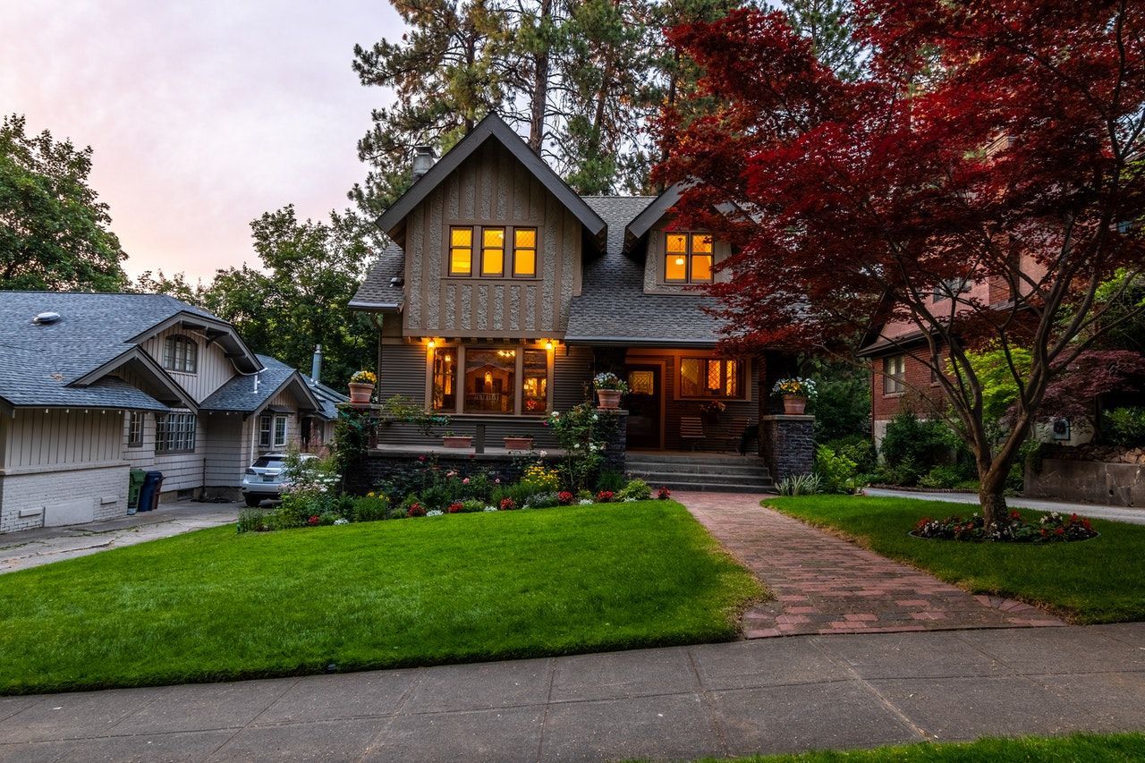 A house with a lush green lawn and a tree in front of it