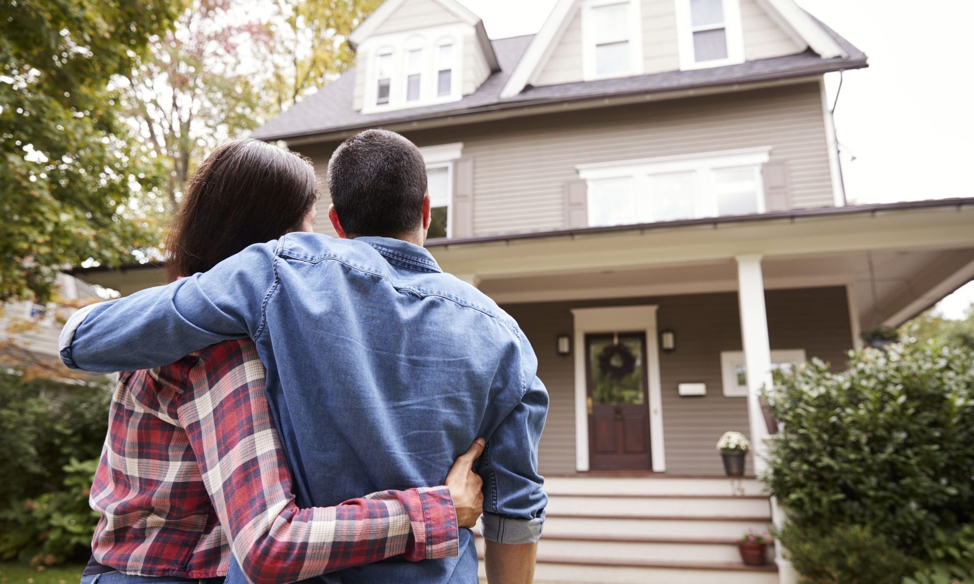 A man and a woman are standing in front of a house.