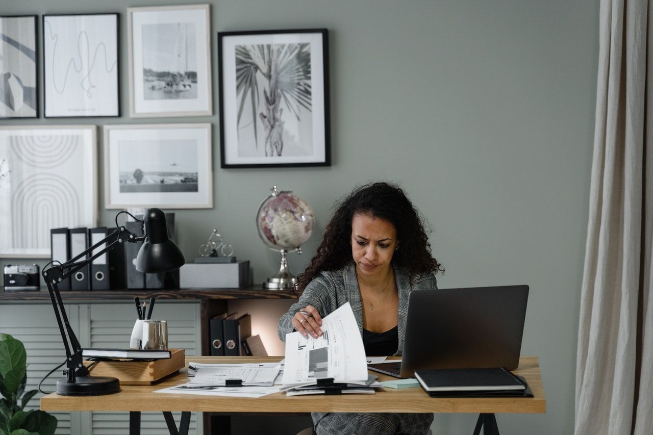 A woman is sitting at a desk with a laptop and papers.