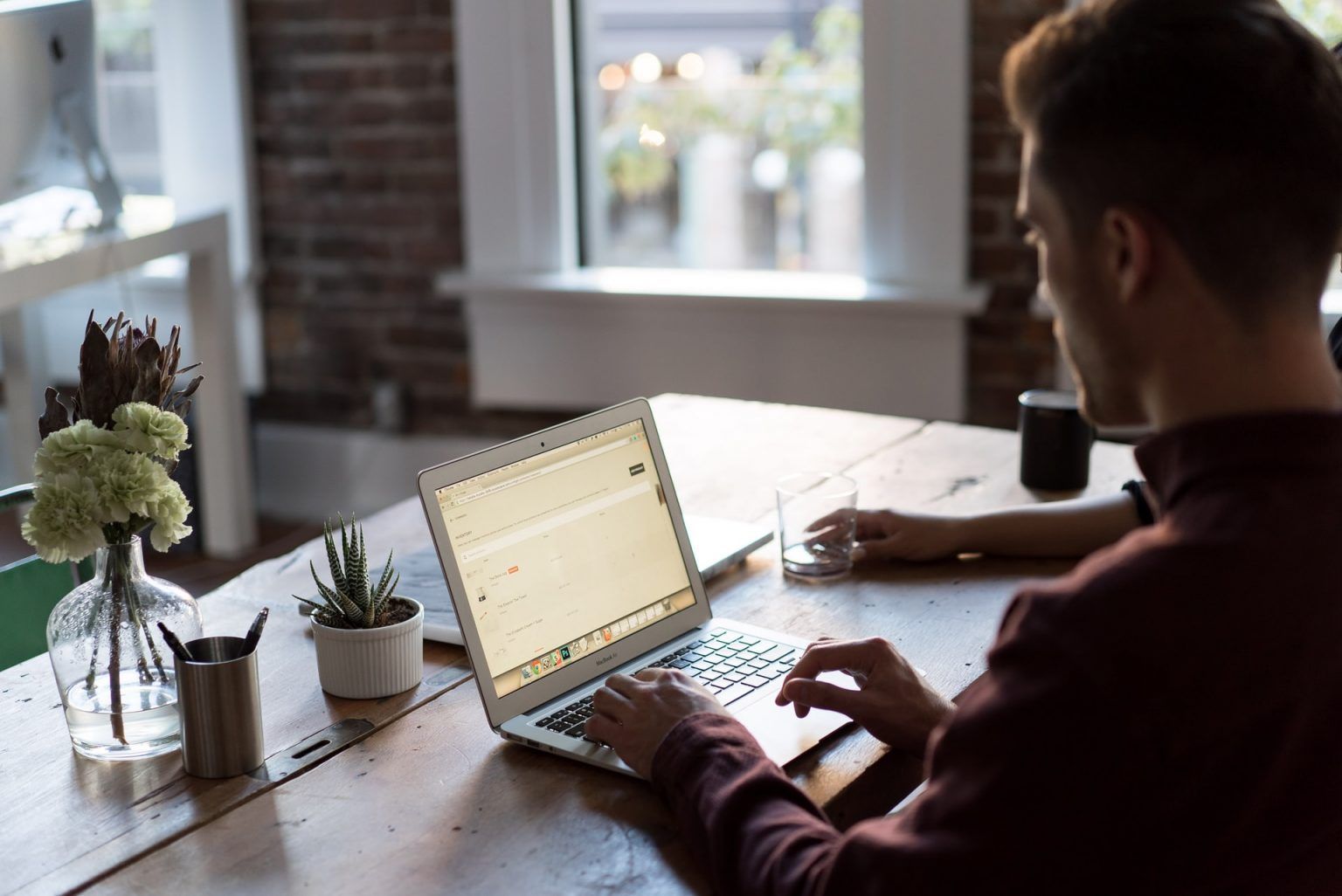 A man is sitting at a table using a laptop computer.