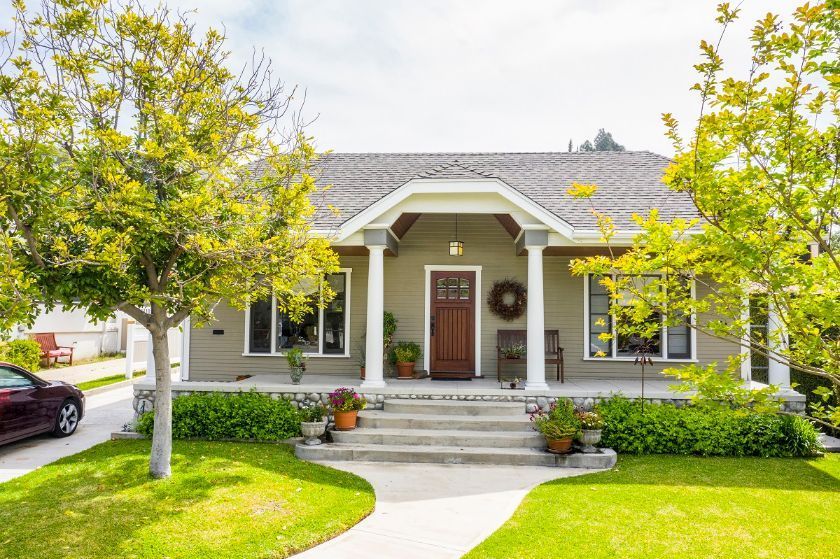 A house with a porch and a car parked in front of it.