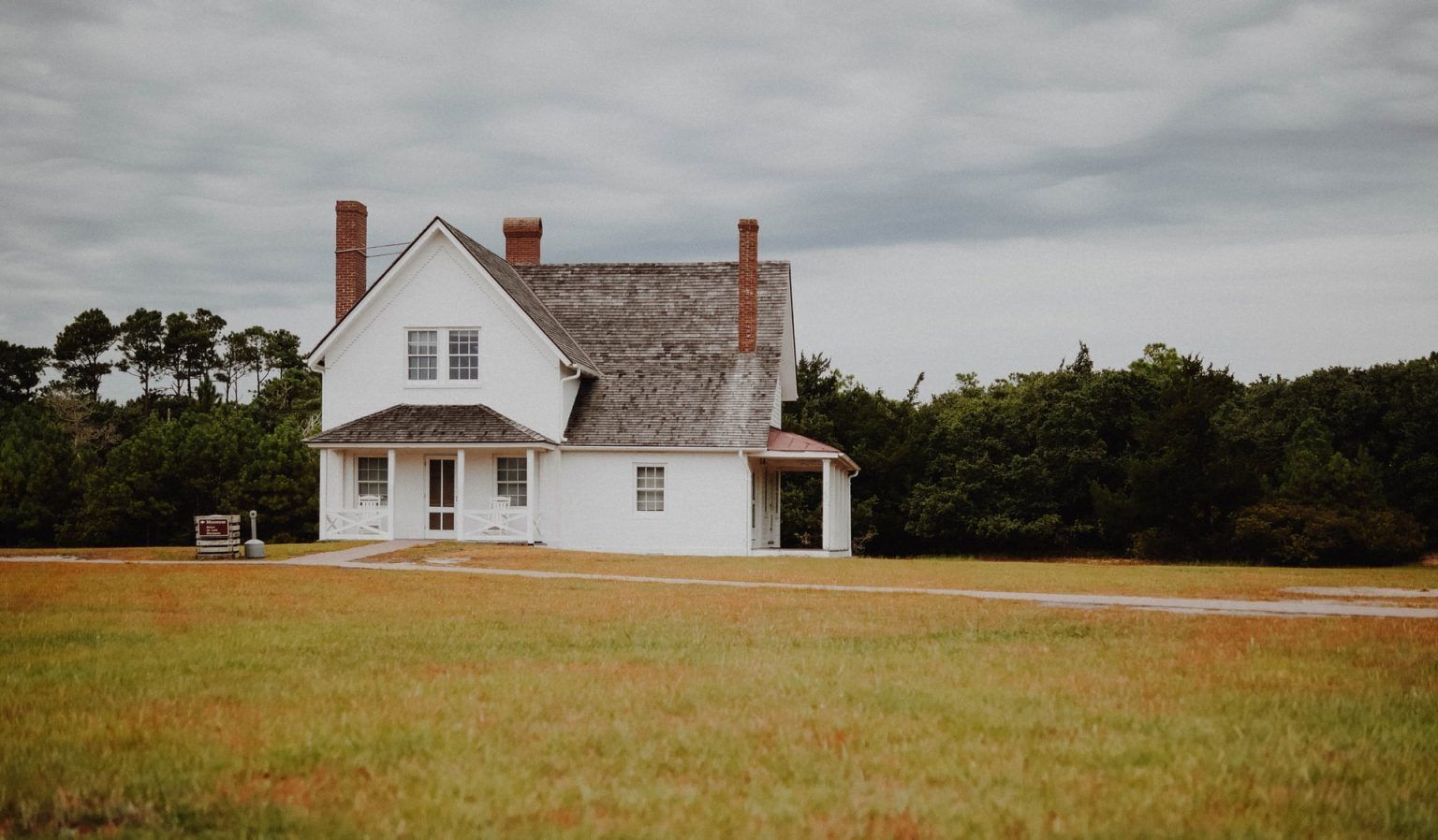 A white house is sitting in the middle of a grassy field.