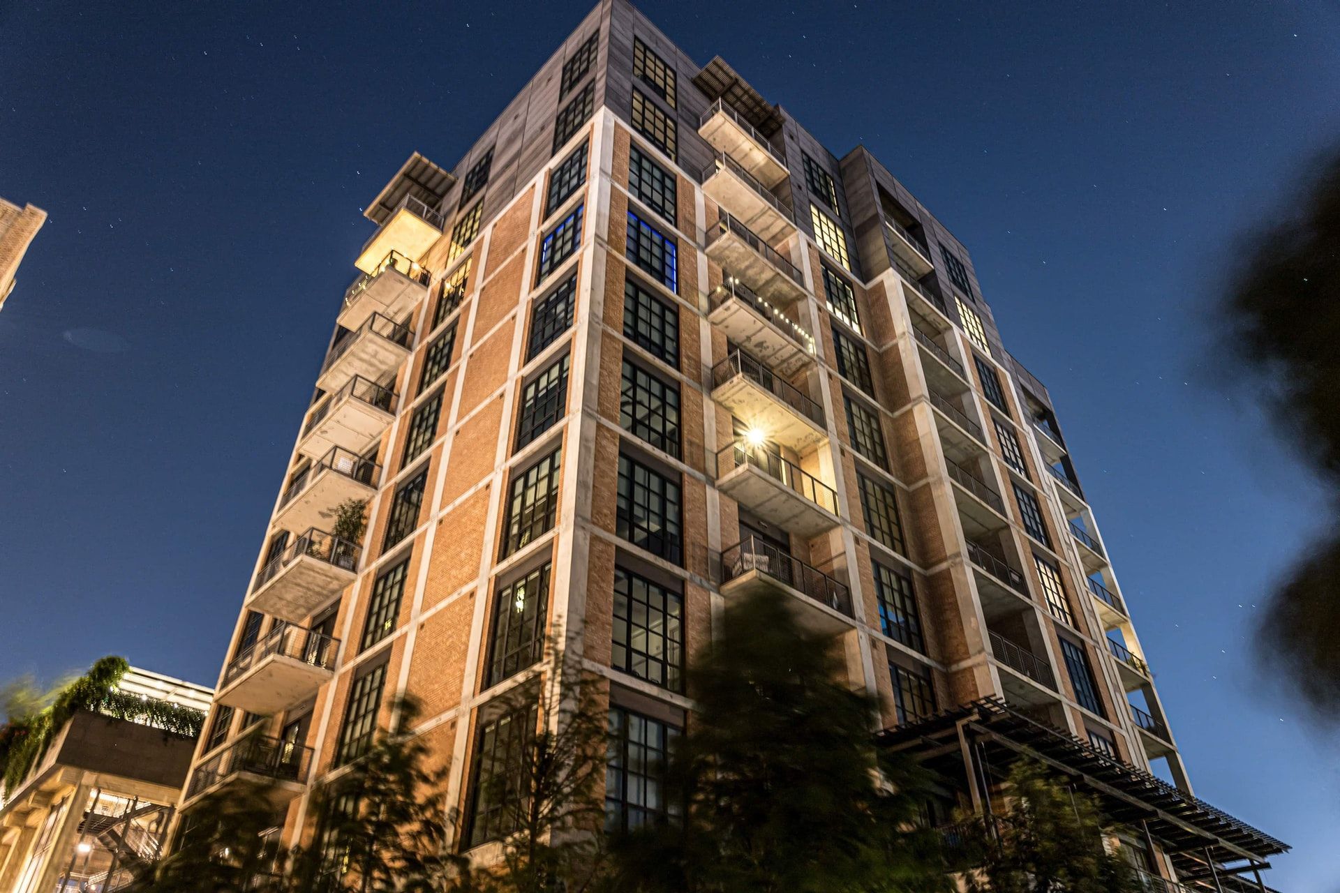 A tall building with a lot of windows is lit up at night.