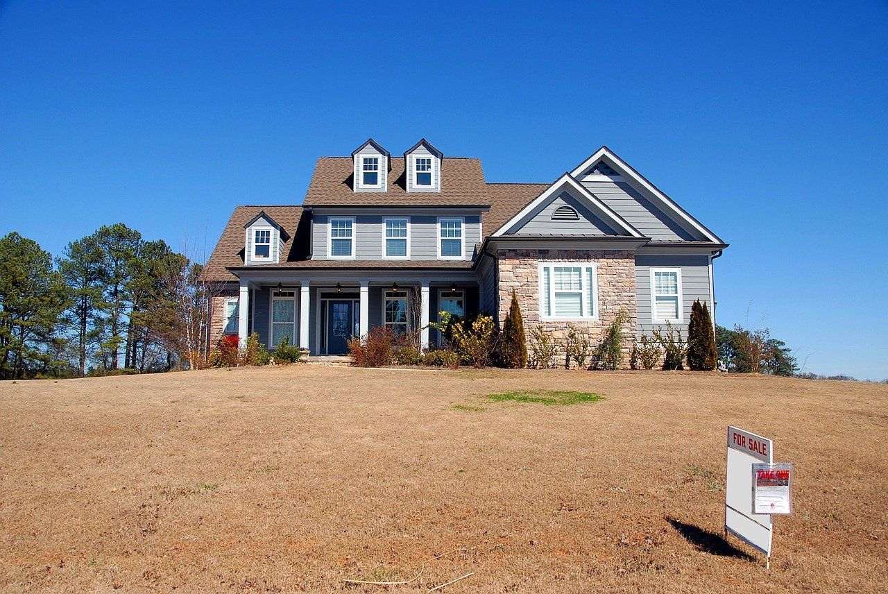 A large house with a for sale sign in front of it