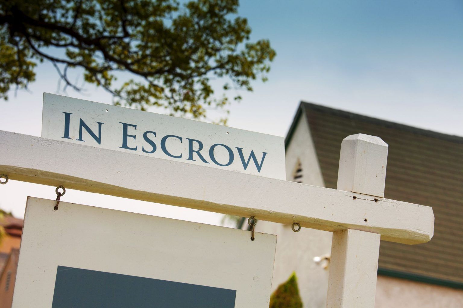 A white sign that says in escrow on it