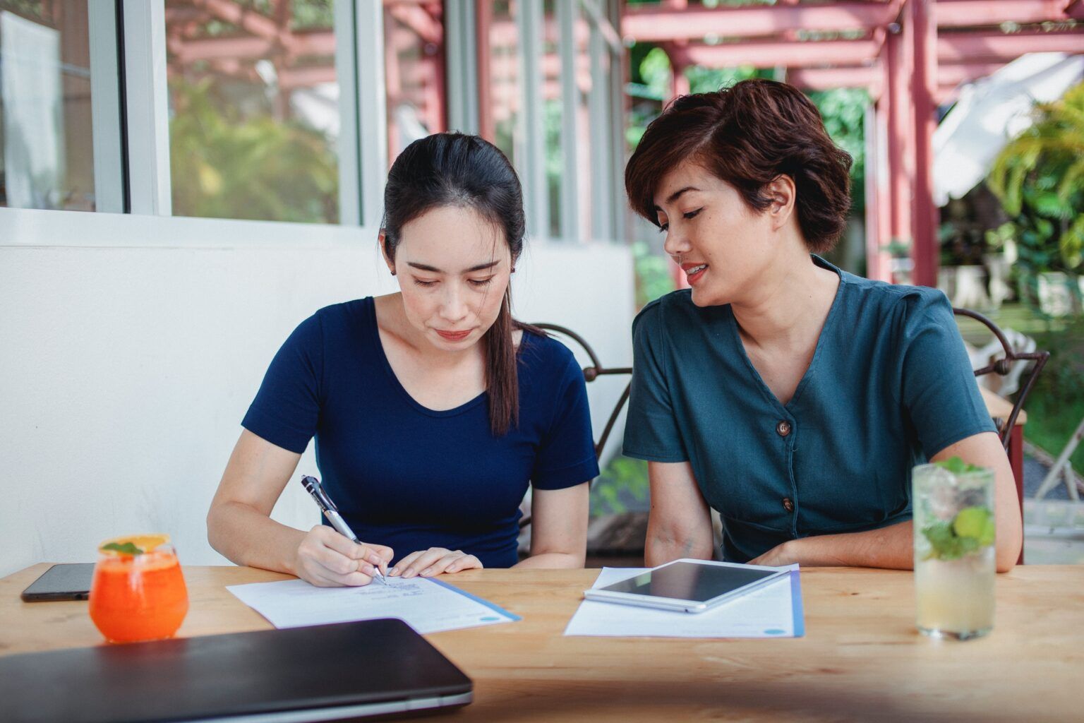 Two women are sitting at a table looking at a piece of paper.