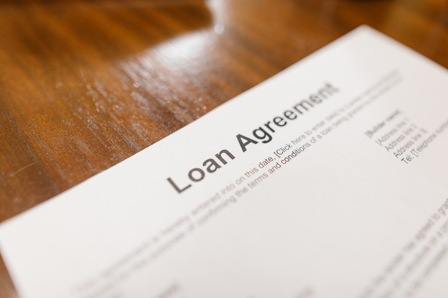 A loan agreement is sitting on a wooden table.