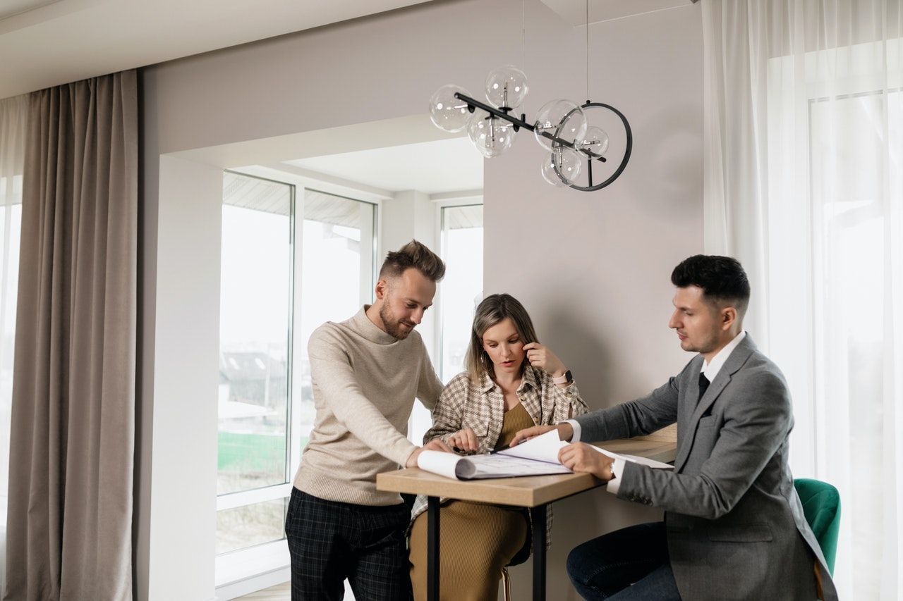 A man and a woman are sitting at a table talking to a real estate agent.