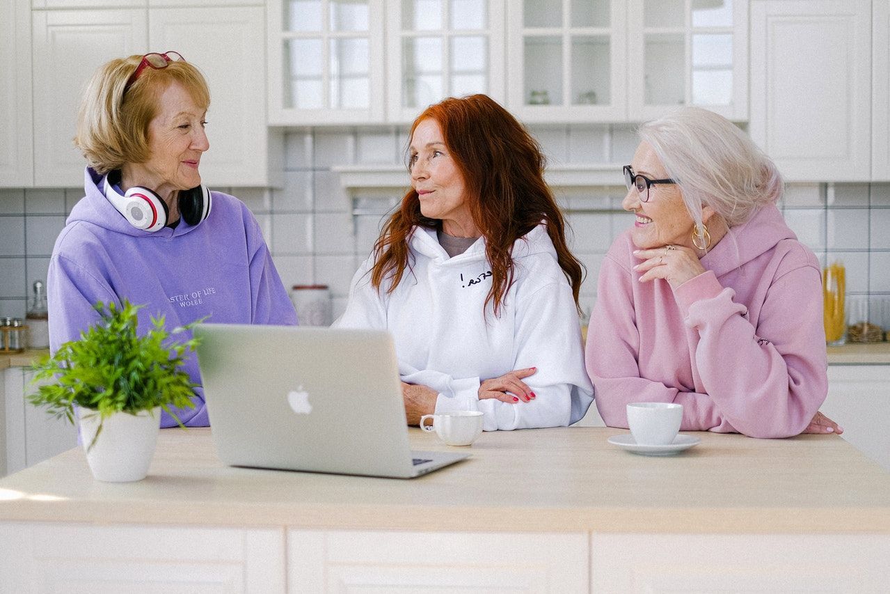 Three women are sitting at a table in front of a laptop computer.