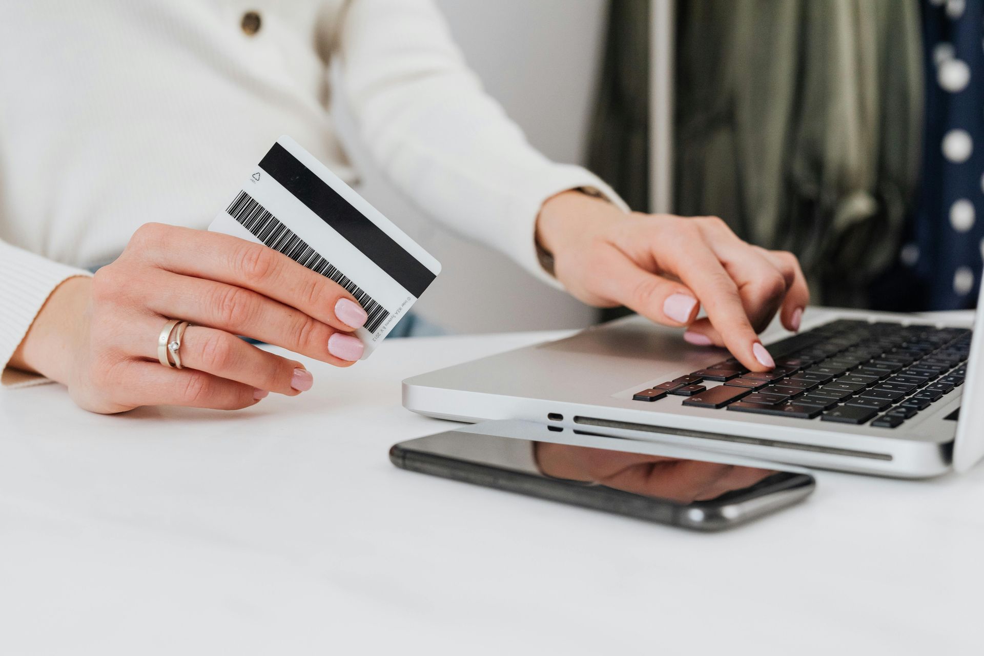 A woman is holding a credit card and using a laptop computer.