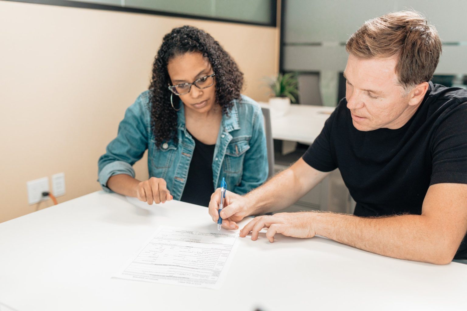 A man and a woman are sitting at a table looking at a piece of paper.