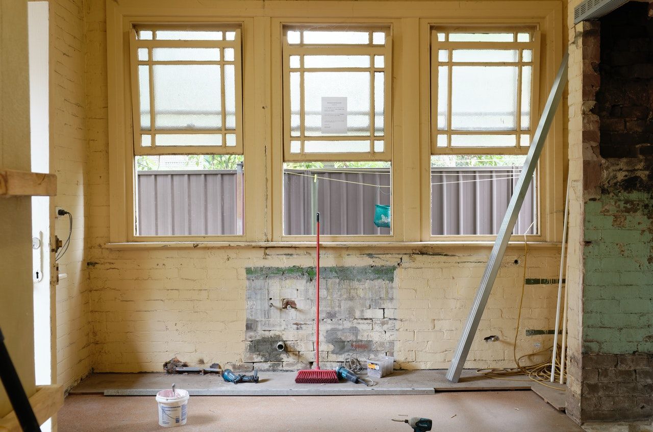 A room with a lot of windows and a broom on the floor.