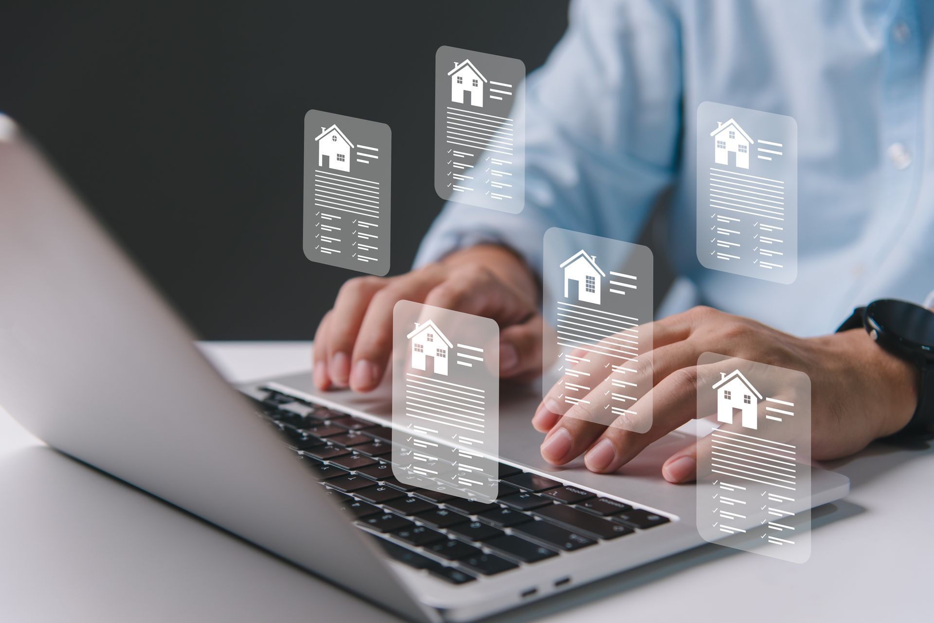 A man is typing on a laptop computer with houses coming out of the screen.