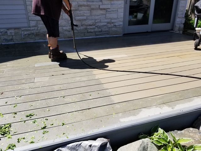 Photo showing person power washing deck