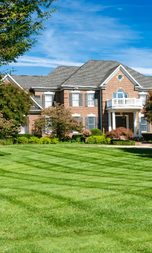 A large brick house with a lush green lawn in front of it.