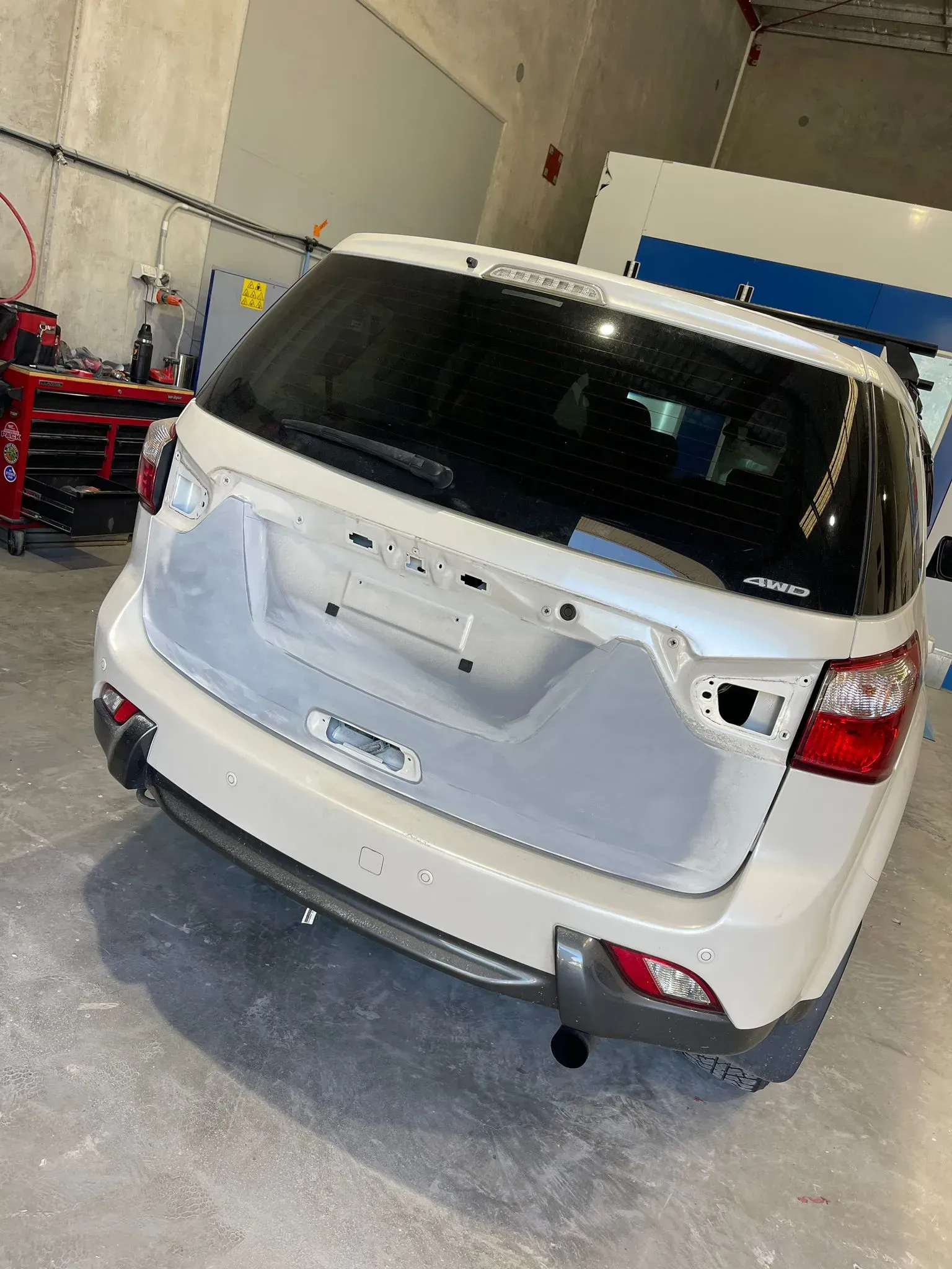 White SUV with rear hatch open, in a repair shop. Primer applied to some body panels. — Coolum Smash Repairs in Coolum Beach, QLD