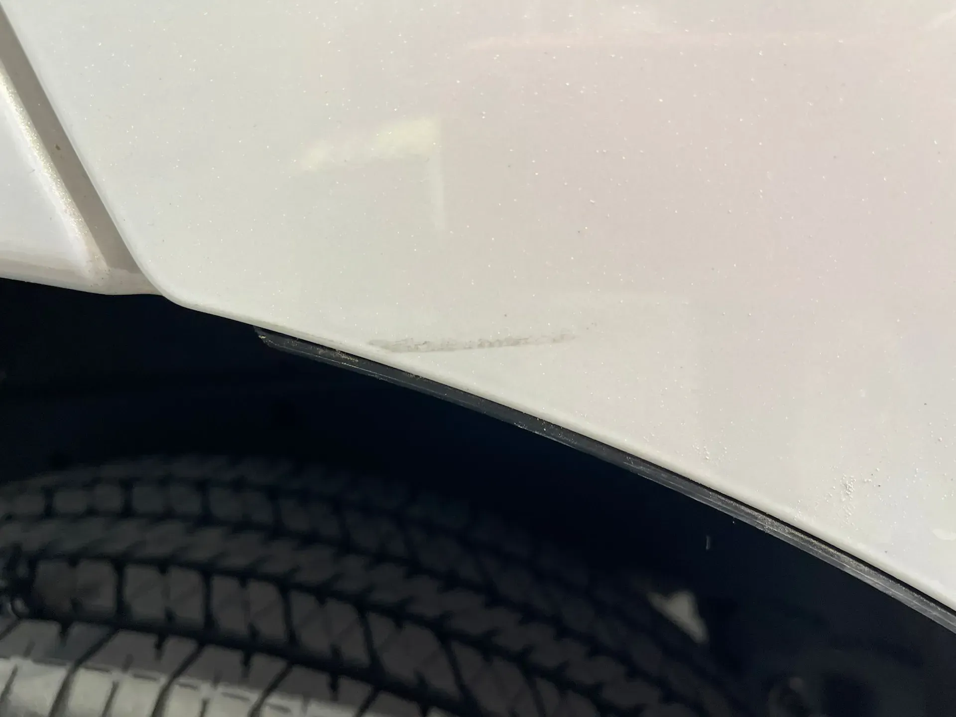 White car fender with a small scratch above a black tire. — Coolum Smash Repairs in Coolum Beach, QLD