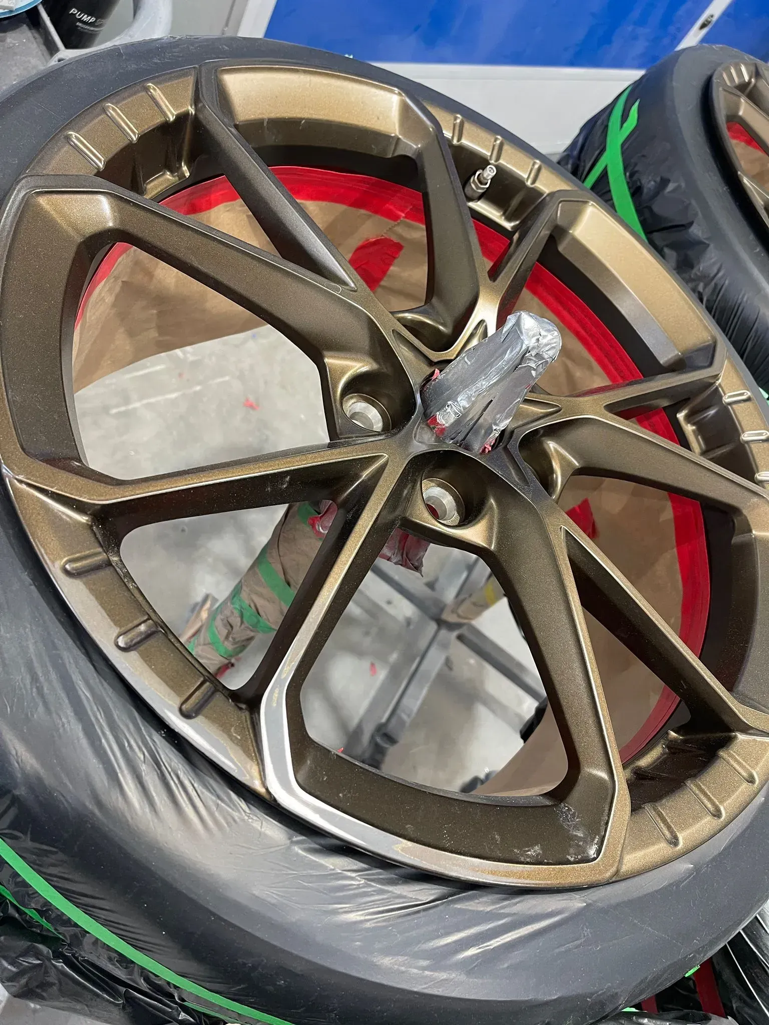Bronze car wheel with red detail and a tool, wrapped in plastic. — Coolum Smash Repairs in Coolum Beach, QLD