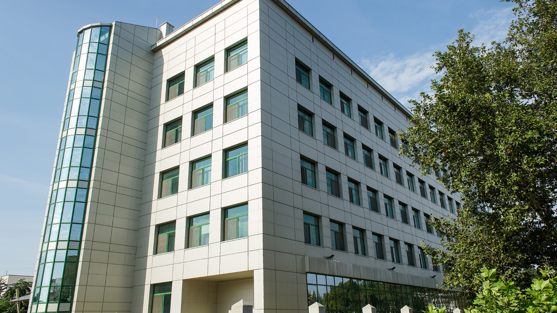 A tall building with lots of windows and a tree in front of it